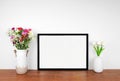 Mock up landscape black frame with vases of cut flowers on a wood shelf Royalty Free Stock Photo