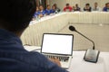 Mock up laptop computer with blank screen on table in meeting room with blur people in background. Business speaker talking with Royalty Free Stock Photo