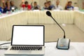 Mock up laptop computer with blank screen on table in meeting room with blur people in background.