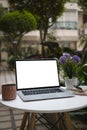 Laptop computer with white screen on round table at outdoor cafe. Royalty Free Stock Photo