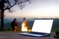 Laptop computer wooden table near campfire and tent. Royalty Free Stock Photo