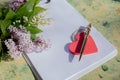 Mock up letter about love.Red wooden heart lies on blank white paper on a wooden table with spring flowers, a greeting Royalty Free Stock Photo