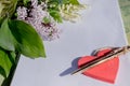 Mock up letter about love.Red wooden heart lies on blank white paper on a wooden table with spring flowers, a greeting Royalty Free Stock Photo