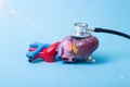 Mock-up of a man's heart on which a stethoscope lies, blue background. The concept of cardiac care in clinics for the