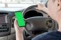 Mock up of man using mobile smart phone inside a car. Driver hand holding blank green screen smartphone, searching address and pin Royalty Free Stock Photo