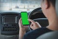 Mock up of man using mobile smart phone inside a car. Driver hand holding blank green screen smartphone, searching address and pin Royalty Free Stock Photo