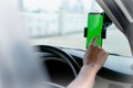 Mock up of man using mobile smart phone inside a car. Driver hand holding blank green screen smartphone, searching address and pin Royalty Free Stock Photo