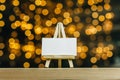 Mock Up mini easel with a white business card. Against the backdrop of a bokeh of stars garland