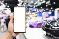 Mock up mobile phone. Hand holding smartphone with  Blurred image of public event exhibition hall showing cars and automobiles. Royalty Free Stock Photo