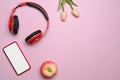 Mobile phone, headphone, apple and pink tulips on pink background. Royalty Free Stock Photo