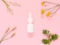 A mock-up of a nasal spray and various field plants on a pink background. The concept of means of protection and treatment of