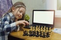 Mock-up online chess courses for children. Child with a chessboard and laptop. Little girl plays chess on the internet. Games for