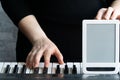 Mock up for online courses play the piano. One hand plays on the keyboard  the other holds the tablet  the screen turned forward. Royalty Free Stock Photo