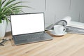 Mock up on an open laptop with a blank white screen, coffee cup and ring binder on a wooden office desk against a white painted Royalty Free Stock Photo