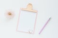 mock up pink clipboard, pen, and chrysanthemum flower on a white table. Space for text