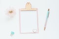 mock up pink clipboard, pen, and chrysanthemum flower on a white table. Space for text