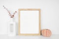 Mock up portrait wooden frame with autumn decor on a white shelf against a white wall