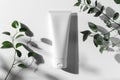 A mock up of realistic white blank cosmetic tube on white and grey background with leafs of plants Royalty Free Stock Photo