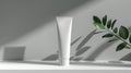 A mock up of realistic white blank cosmetic tube on white and grey background with leafs of plants Royalty Free Stock Photo