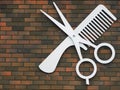 Hairdressing: scissors and comb emblem hanging on a brick wall