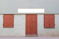 Mock up signboard on facade of the old house with old wooden door and two closed windows. Royalty Free Stock Photo