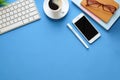 Mock up smart phone, glasses, keyboard, coffee cup, and notebook on blue background Royalty Free Stock Photo