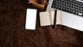 Smart phone with white screen and laptop computer on brown fur rug. Royalty Free Stock Photo