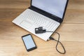 Mock up of a smartphone and an action camera connected to a white laptop on a wooden table background.