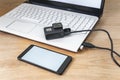 Mock up of a smartphone and an action camera connected to a white laptop on a wooden table background.