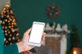 Mock up, a smartphone in the hand of a girl. against the background of the New Year and Christmas interior with decorations on the Royalty Free Stock Photo