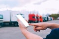 Mock up a smartphone in the hands of a man. Against the background of red trucks. Logistics concept.