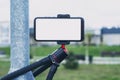 Mock-up of a smartphone with a white screen on a tripod outdoors Royalty Free Stock Photo