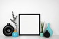 Mock up black frame with black and blue decor on a white shelf against a white wall Royalty Free Stock Photo