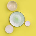 Mock up table setting on yellow background. Group of trendy ceramic utensil with plate, bowl and sauser Royalty Free Stock Photo