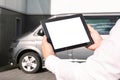 Mock up technology. Businessman in a white shirt holds a tablet with a white screen on the background of a minibus