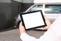 Mock up technology. Businessman in a white shirt holds a tablet with a white screen on the background of a minibus