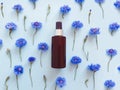 Mock-up of unbranded brown plastic spray bottle and blue cornflowers on a pastel blue background. Cosmetic bottle container Royalty Free Stock Photo