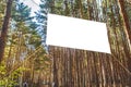 Mock up white blank billboard on the background of fir trees in a forest camp