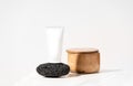 Mock up white cosmetics tube on black volcanic pumice lying on bathroom table.