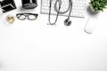 Mock up of white doctors desk with stethoscope, keyboard, mouse, glass and pen.Top view with copy space