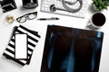 Mock up of white doctors desk with stethoscope, keyboard, mouse, glass, xray film and blank screen smart phone.Top view with copy Royalty Free Stock Photo