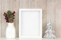 Mock up white frame with Christmas branches and silver tree on a shelf against a rustic gray wood wall