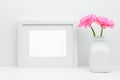 Mock up white frame and pink daisy flowers in vase against white wall on shelf Royalty Free Stock Photo