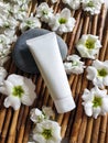 Mock up of white plastic bottle tube with white flowers and stone on a bamboo background. Royalty Free Stock Photo