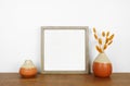 Mock up wood frame with autumn branches and home decor on a wooden shelf against a white wall