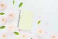 Mock up yellow notebook, pink plastic hearts and pink chrysanthemum flowers and green leaves on a white table. Royalty Free Stock Photo