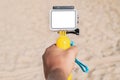 Mockup of an action camera in a man& x27;s hand. Beach sand in the background