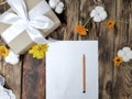 Mockup autumn flatlay composition with gift box, flowers, empty card on wooden table.