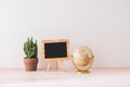 Mockup blackboard frame, globe, cactus on well arranged desk Royalty Free Stock Photo