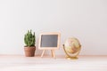 Mockup blackboard frame, globe, cactus on well arranged desk Royalty Free Stock Photo